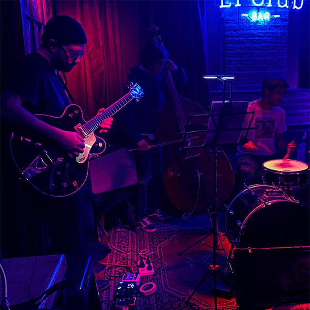 Foto de Pablo Cúbico, fundador da Music Teacher Studio, tocando guitarra em um clube de jazz.